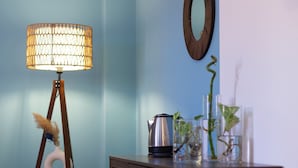 Une pièce avec un mur bleu, une armoire en bois, un lampadaire et un miroir.