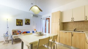 Een moderne keuken met houten kastjes, een eettafel met stoelen en een hanglamp.