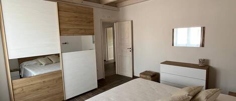 Een slaapkamer met een bed, een kast, een nachtkastje en een spiegel aan de muur.