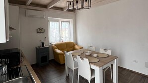 A modern kitchen with a dining area, featuring a wooden ceiling, a built-in stove, and a dining table with chairs.