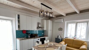 A modern kitchen with white cabinets, a wooden dining table, and a yellow sofa.