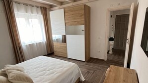 A bedroom with a bed, wooden wardrobe, and a small table with a jar.