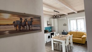 A spacious living area with a dining table and chairs, a sofa, and a kitchen area with appliances.