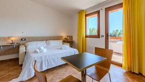 A hotel room with a bed, a table, chairs, a desk, and a window with curtains. - countryside  3 - One Bedroom Guest House, Sleeps 2 (Carbonia)