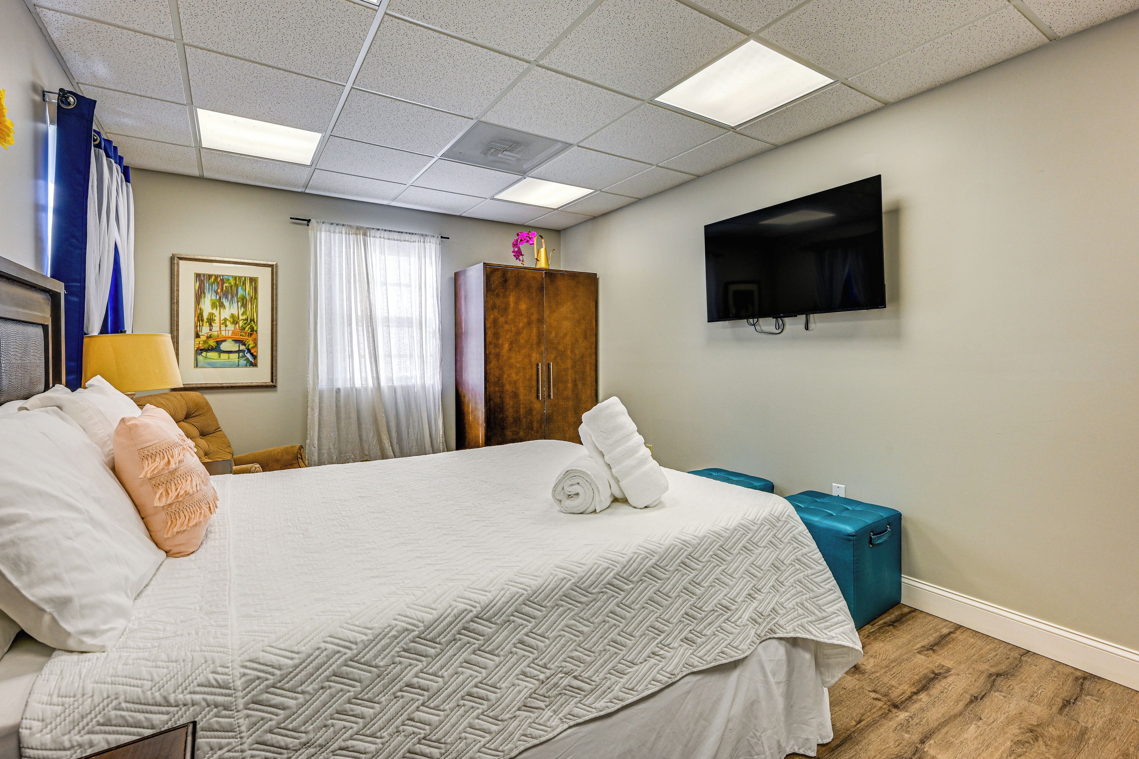 A hotel room with a large bed, a television mounted on the wall, a wardrobe, and a small table.