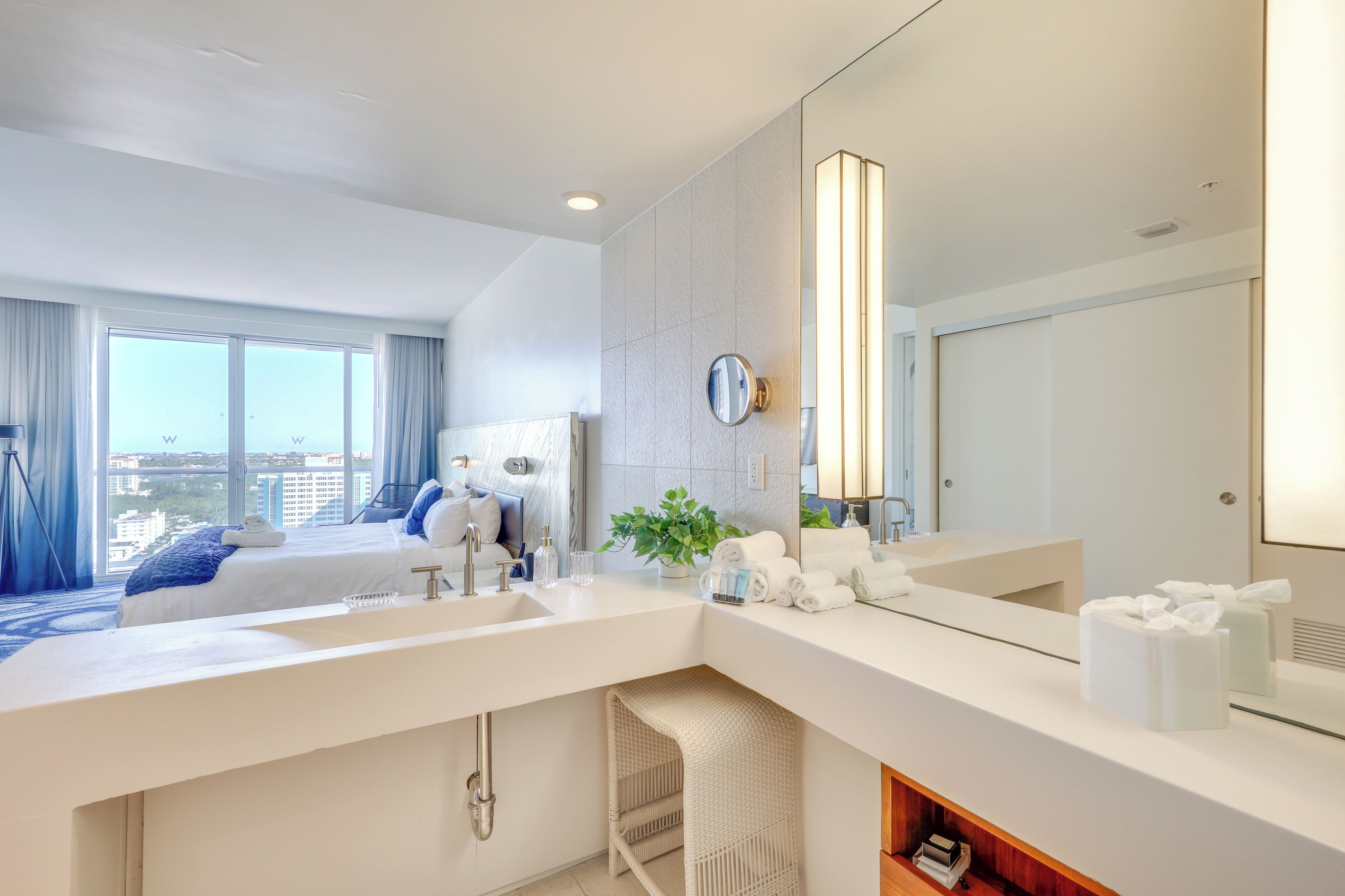 Un baño de hotel moderno con un lavamanos grande, un espejo y vistas a la ciudad.
