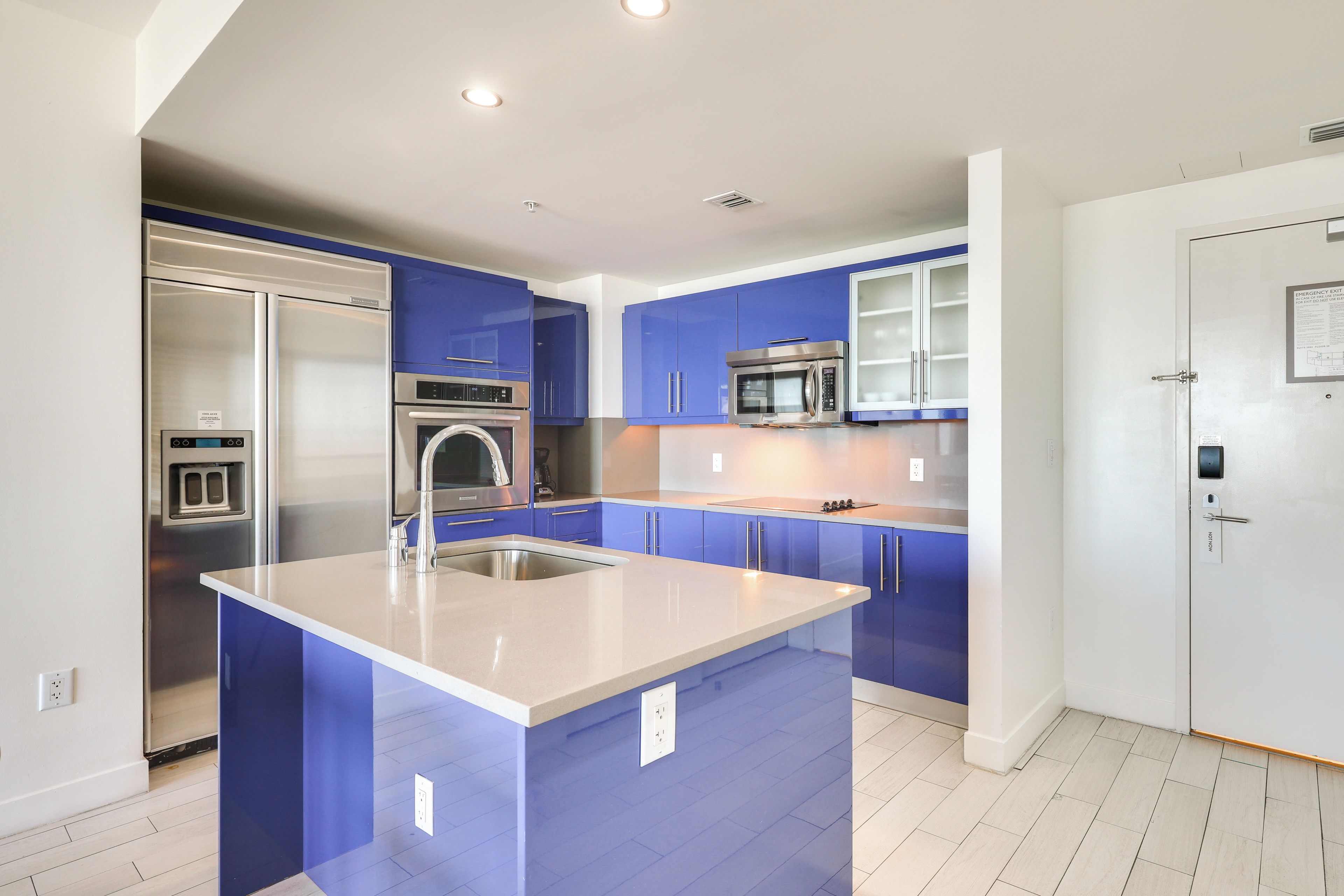 A modern kitchen with blue cabinets, stainless steel appliances, and a large island.