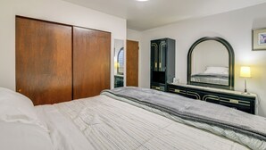 Ein Schlafzimmer mit einem großen Bett, einem Holzschrank und einem Spiegel mit Lampe.
