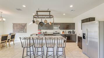 A modern kitchen with a central island, stainless steel appliances, and a hanging pot rack.