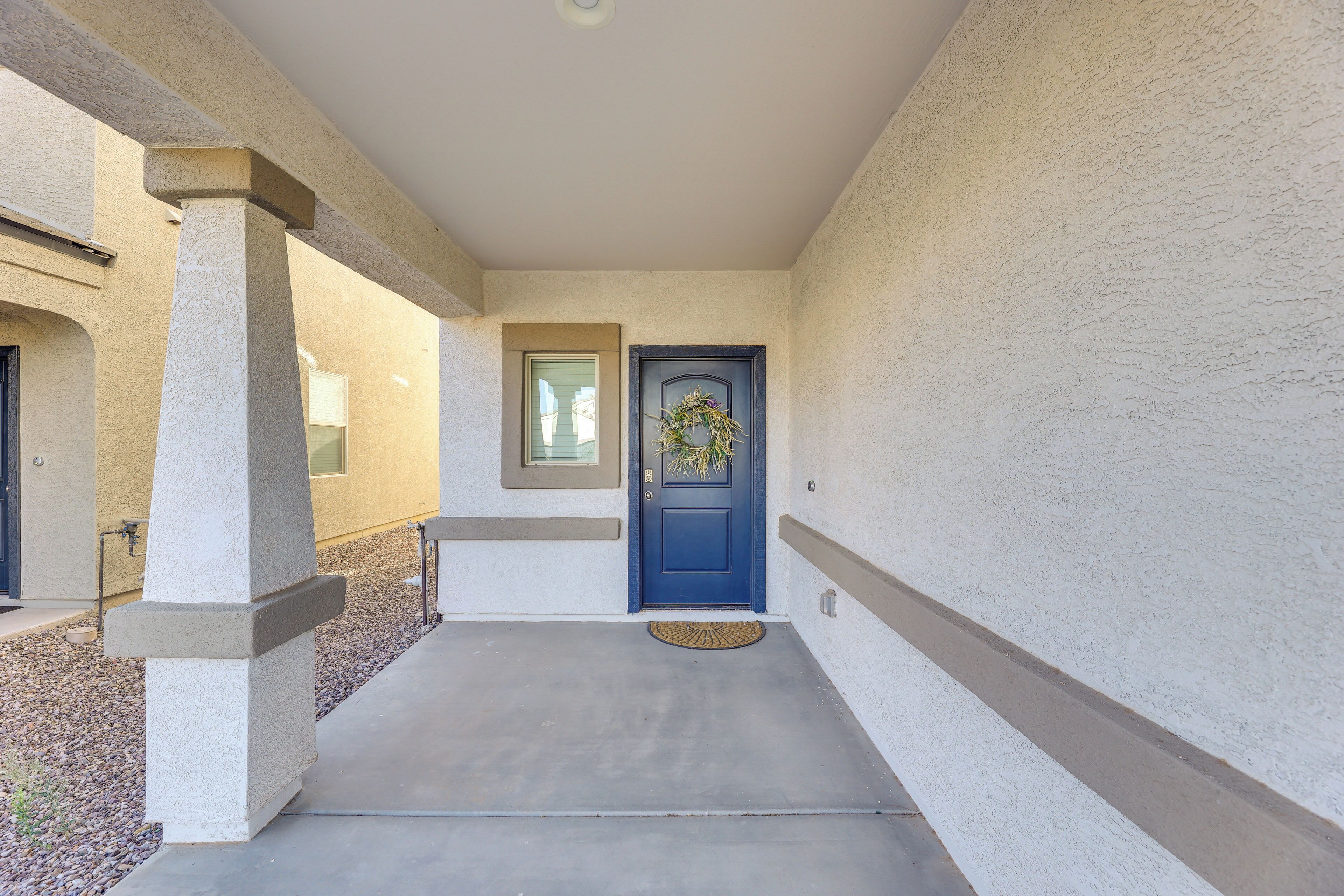 Un couloir avec une porte bleue, une petite fenêtre et un pilier en béton.