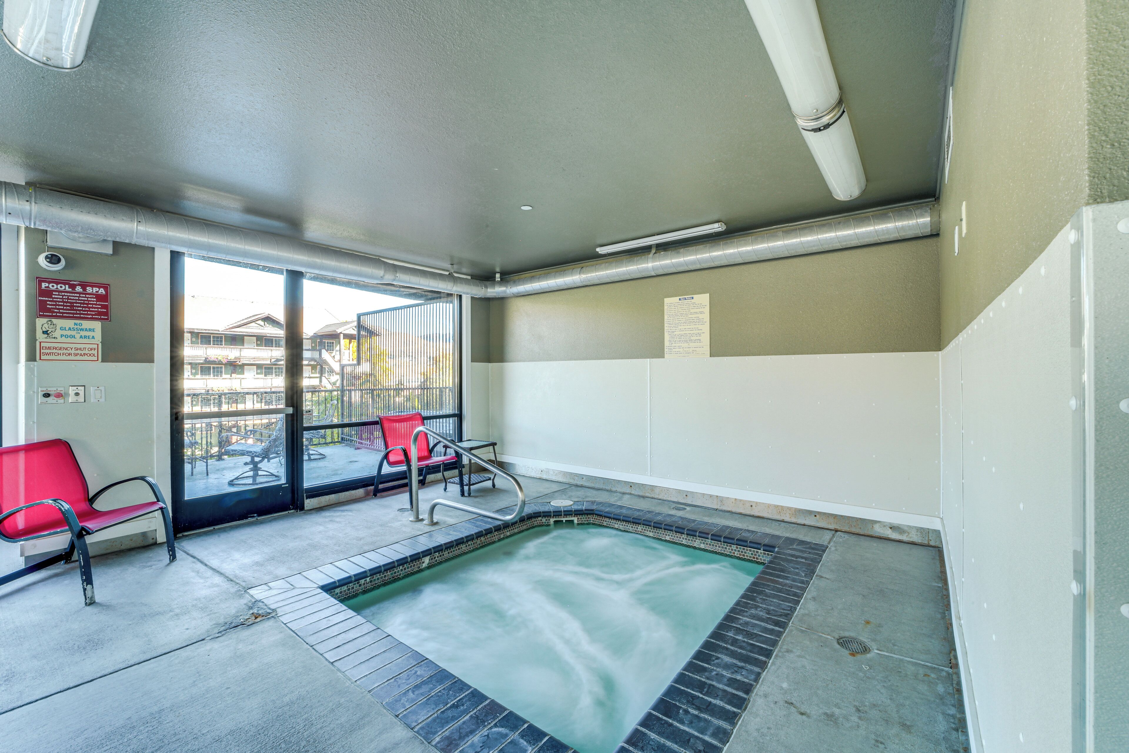 Un área de spa con jacuzzi, sillas rojas y vistas al exterior.