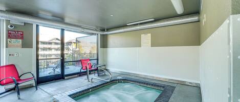 Un área de spa con jacuzzi, sillas rojas y vistas al exterior.