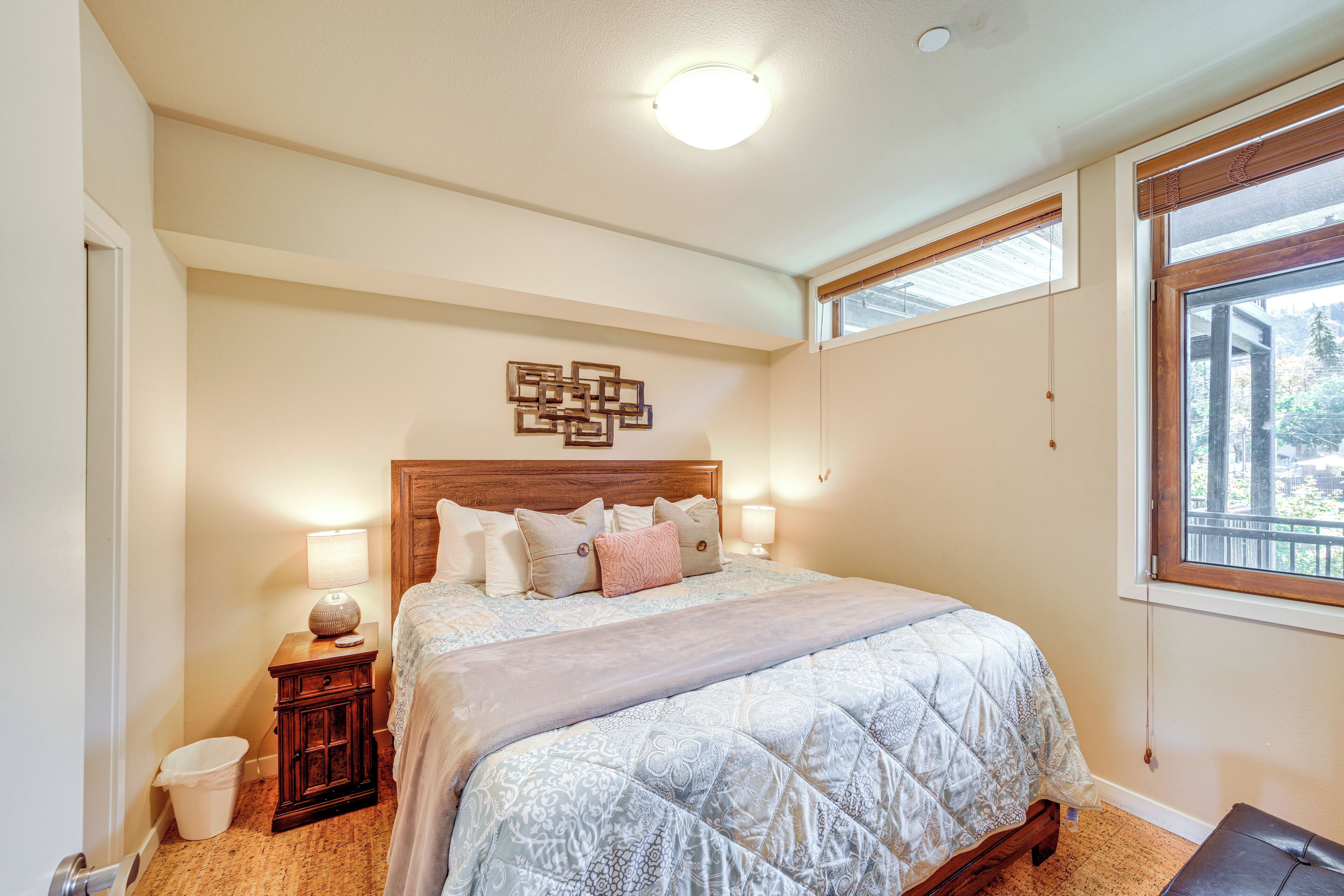 Una camera da letto con un letto grande, una testiera in legno, una lampada a parete e una finestra vista alberi.