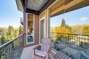 A balcony with a wooden chair and a glass door leading to an interior room. - Walk to the Lake: Chelan Condo w/ Mtn Views! (Chelan)