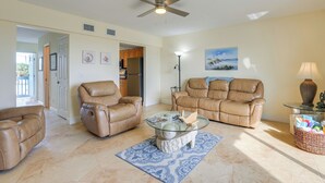 A spacious living room with leather sofas, a glass coffee table, and a ceiling fan. - Oceanside: Beachfront Fort Pierce Retreat (Fort Pierce)