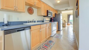 A kitchen with wooden cabinets, a dishwasher, a microwave, and a refrigerator. - Oceanside: Beachfront Fort Pierce Retreat (Fort Pierce)