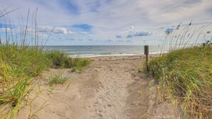 A sandy beach path leading to the ocean, surrounded by grass and a wooden post. - Oceanside: Beachfront Fort Pierce Retreat (Fort Pierce)