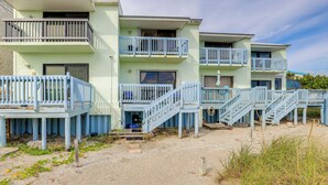 A row of light green multi-story buildings with blue railings and steps, featuring balconies and windows. - Oceanside: Beachfront Fort Pierce Retreat (Fort Pierce)