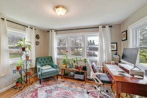 A cozy living room with a green armchair, a wooden desk with a computer, and a large window with curtains. - 1 Mi to Historic District: Mtn-view Franklin Home (Franklin)