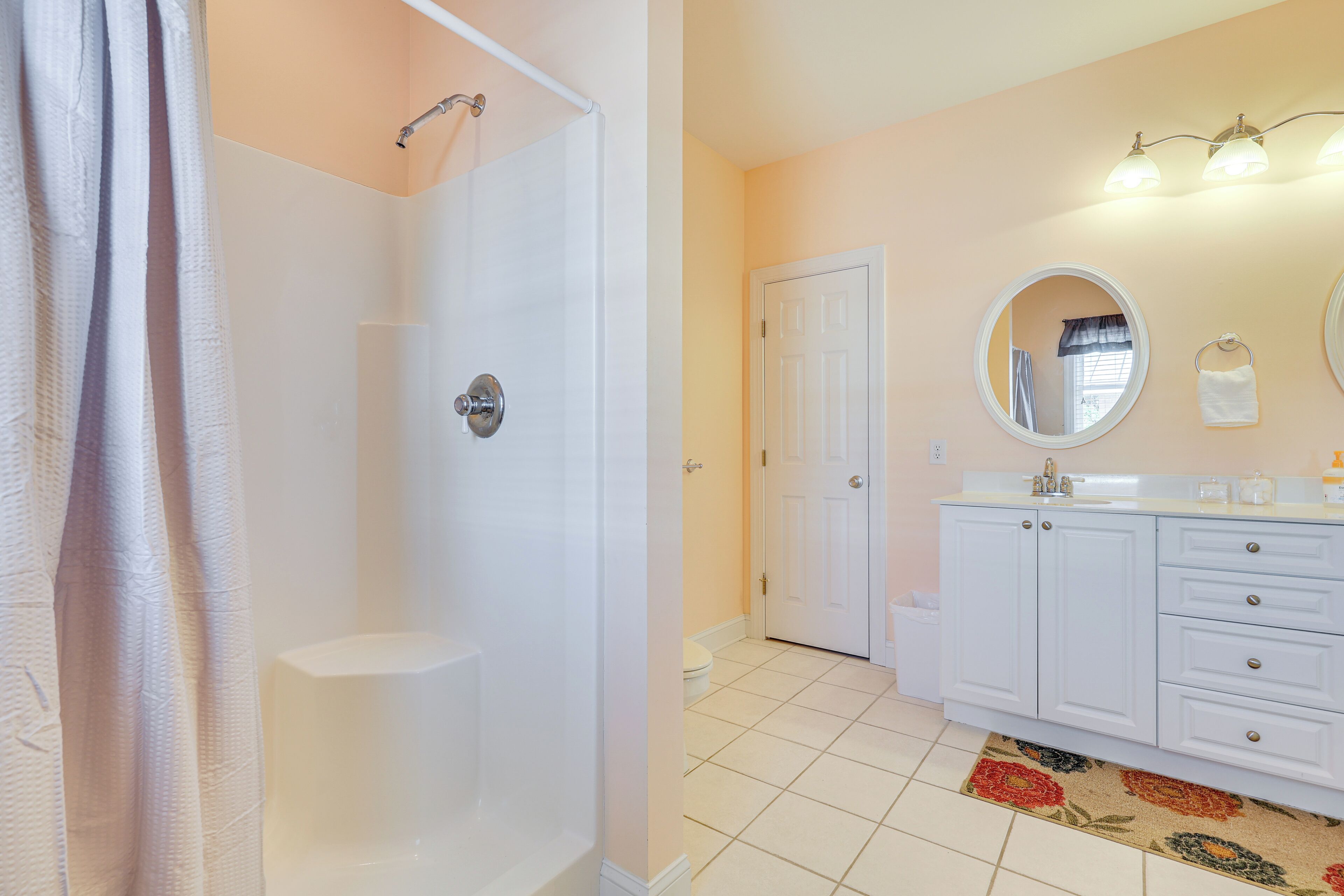 A bathroom with a shower, toilet, sink, and mirror.