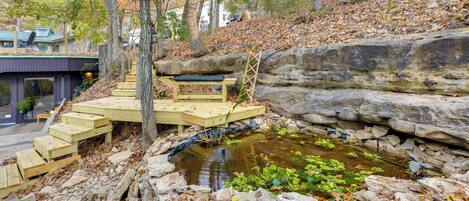 A stone retaining wall, a wooden deck, and a small pond with plants.