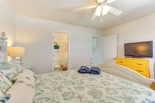 A bedroom with a bed, a ceiling fan, a TV, and a yellow dresser. - Walk to Shore: Ocean View Cape San Blas Townhome (Port St. Joe)