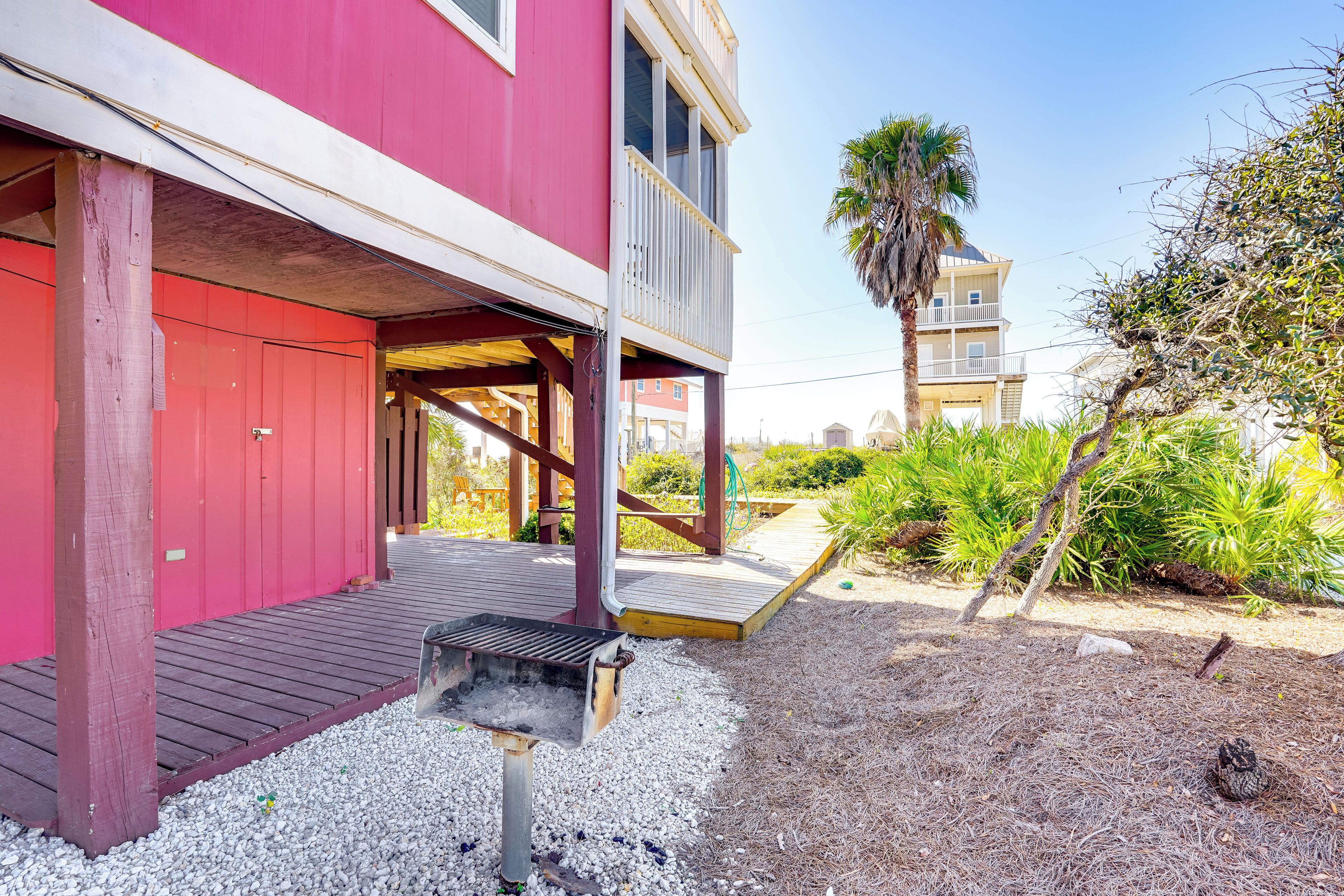 A red building with a wooden deck and a barbecue grill in the foreground.