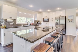 A modern kitchen with white cabinets, a granite countertop, and a stainless steel refrigerator. - 3 Mi to Lake: House w/ Fire Pit in Mountain Home! (Mountain Home)