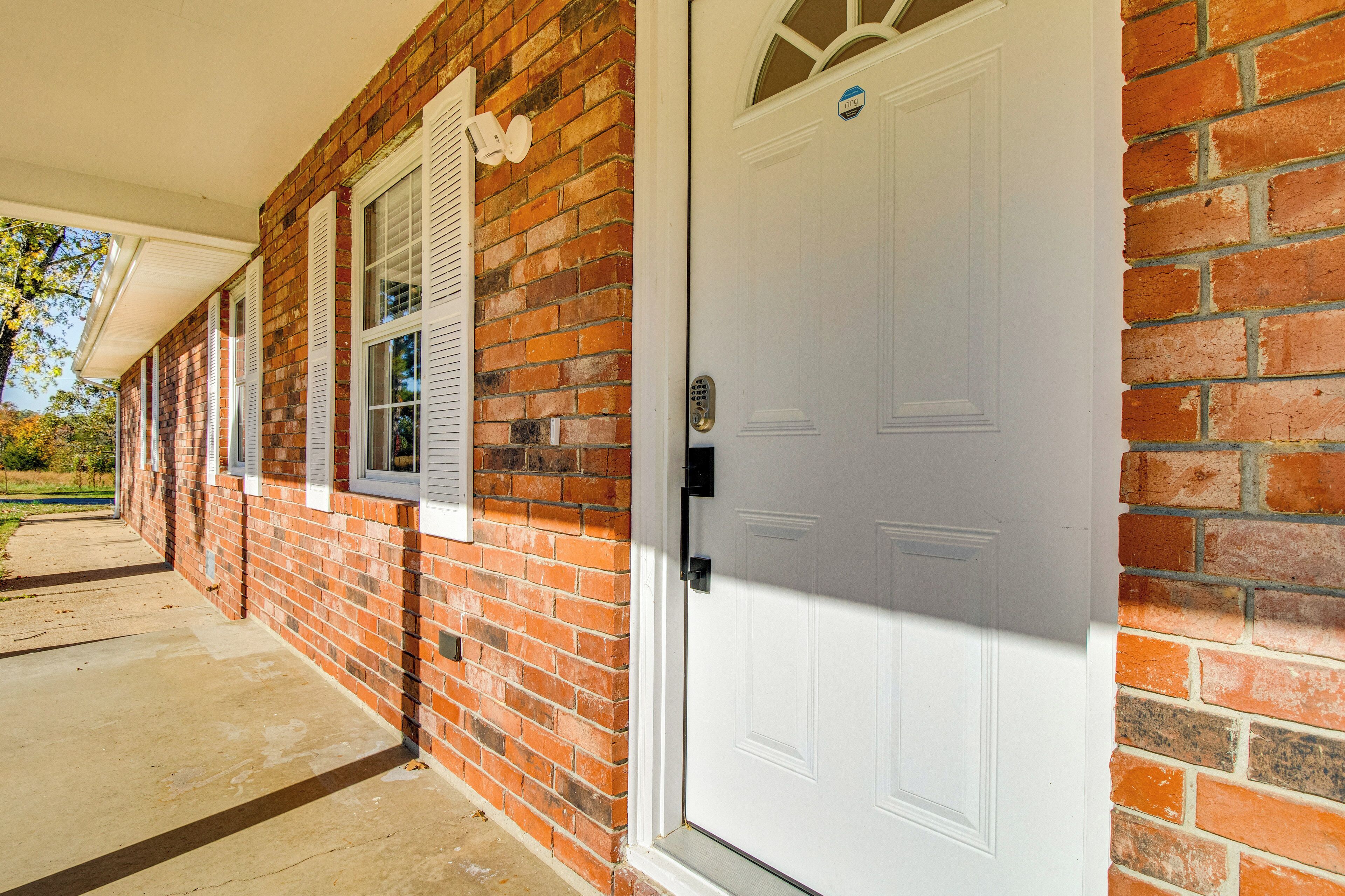 A brick building with a white door and windows with shutters.