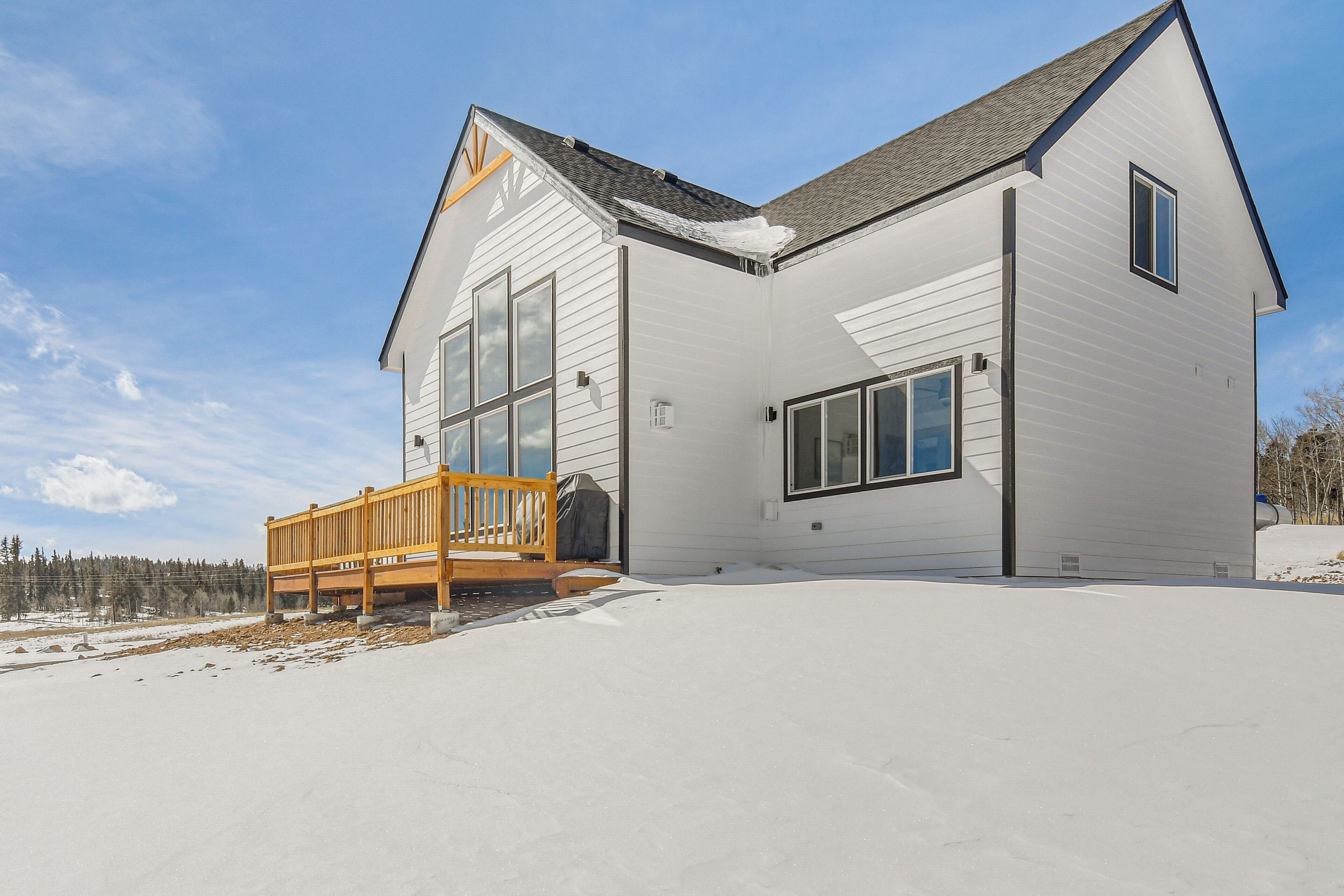 A modern two-story house with a large deck and a covered porch.
