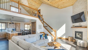 A spacious living area with a large sofa, a wooden staircase, and a kitchen in the background.