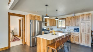 A modern kitchen with wooden cabinets, stainless steel appliances, and a large island with bar stools.