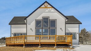 A modern two-story house with a wooden deck and large windows.
