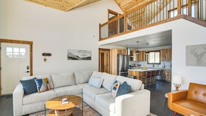 A spacious living area with a large L-shaped sectional sofa, a round coffee table, and a wooden ceiling.