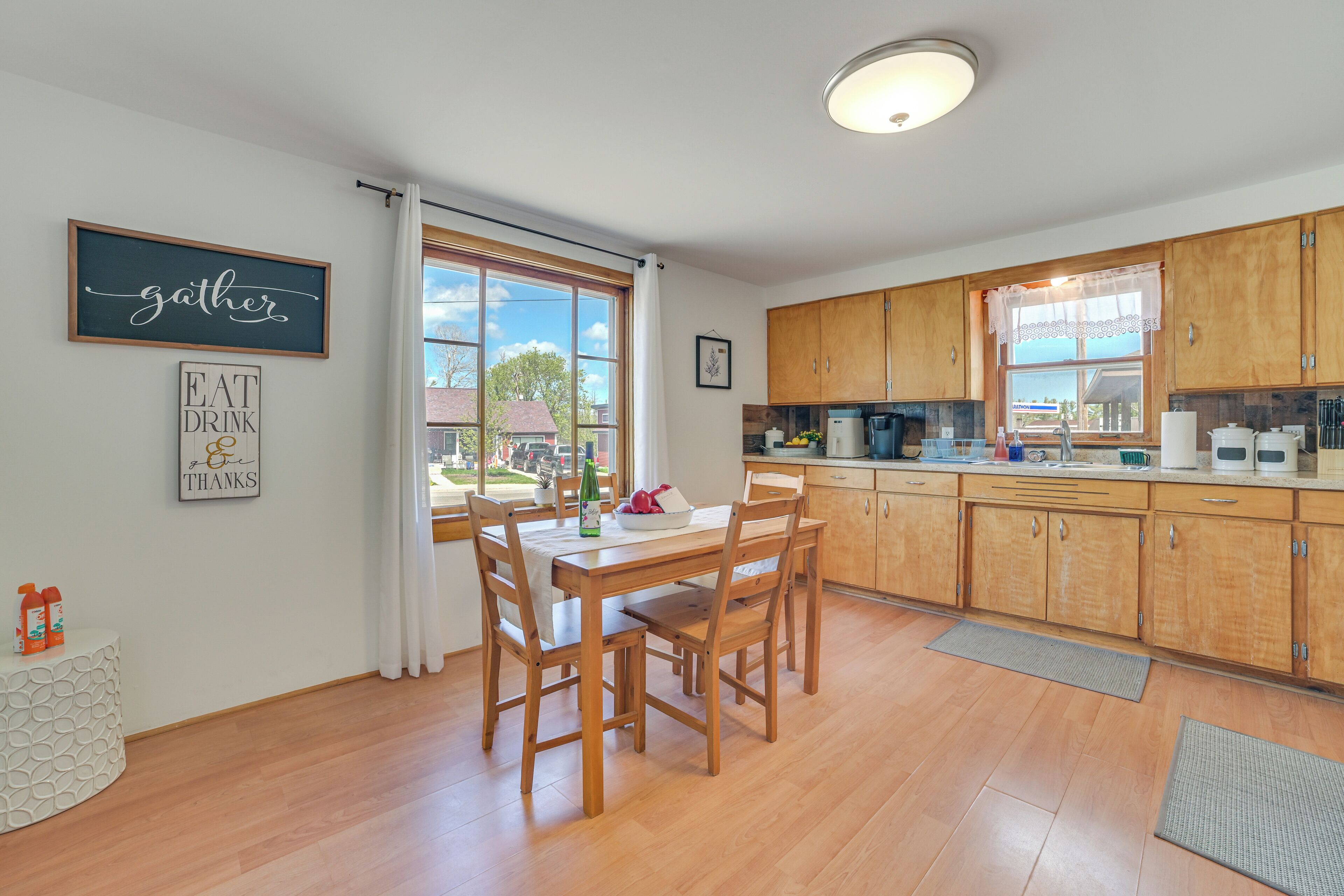 Una cocina moderna con armarios de madera, una mesa de comedor con sillas y una ventana con vistas al exterior.