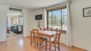 A dining area with a wooden table and chairs, a window with curtains, and a sign that reads "The Best is to Come".