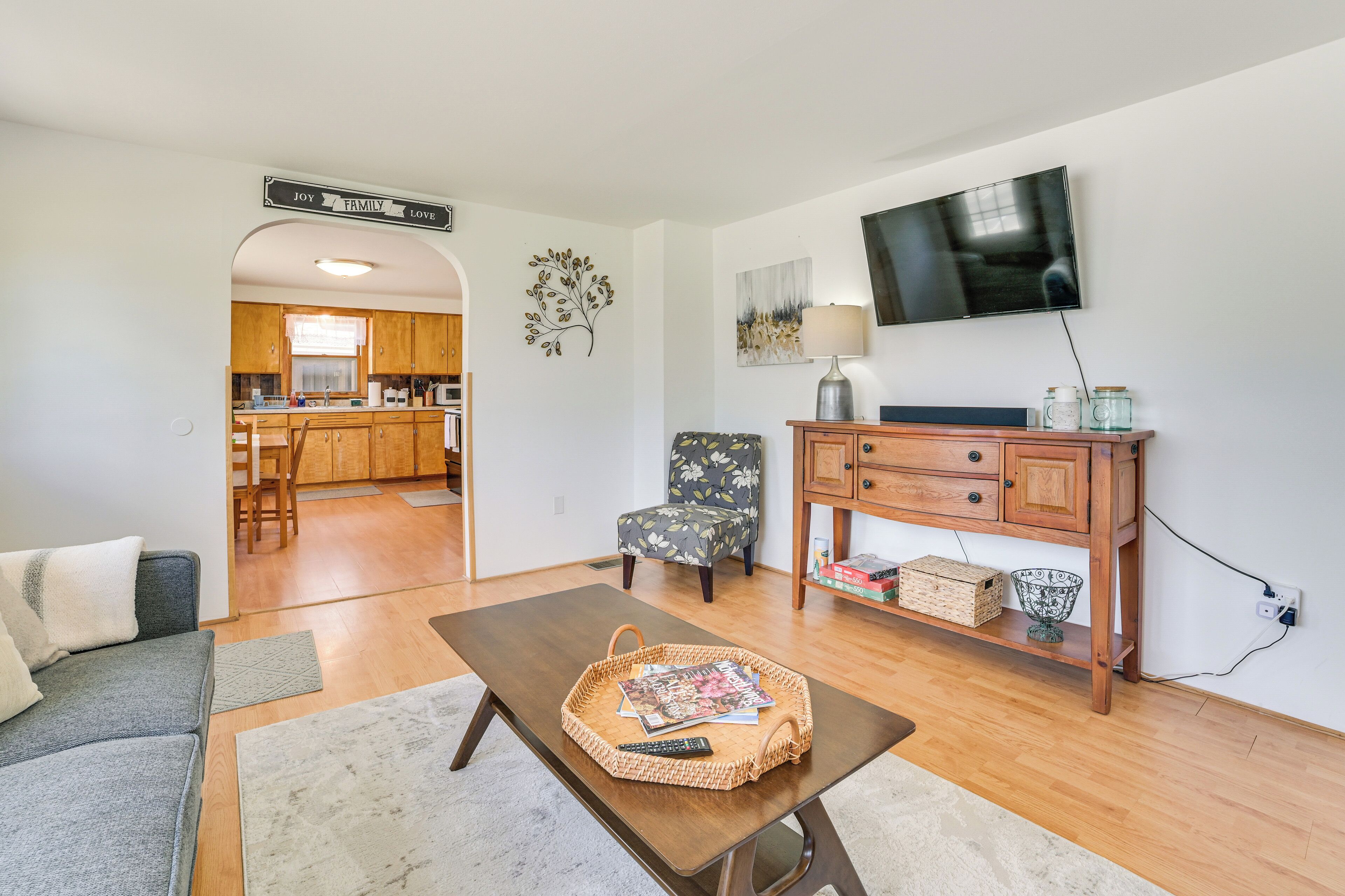 A living room with a sofa, a coffee table with magazines, a TV, and a wooden cabinet with jars.
