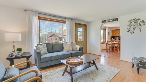 A living room with a grey sofa, a coffee table, and a view of the outside.