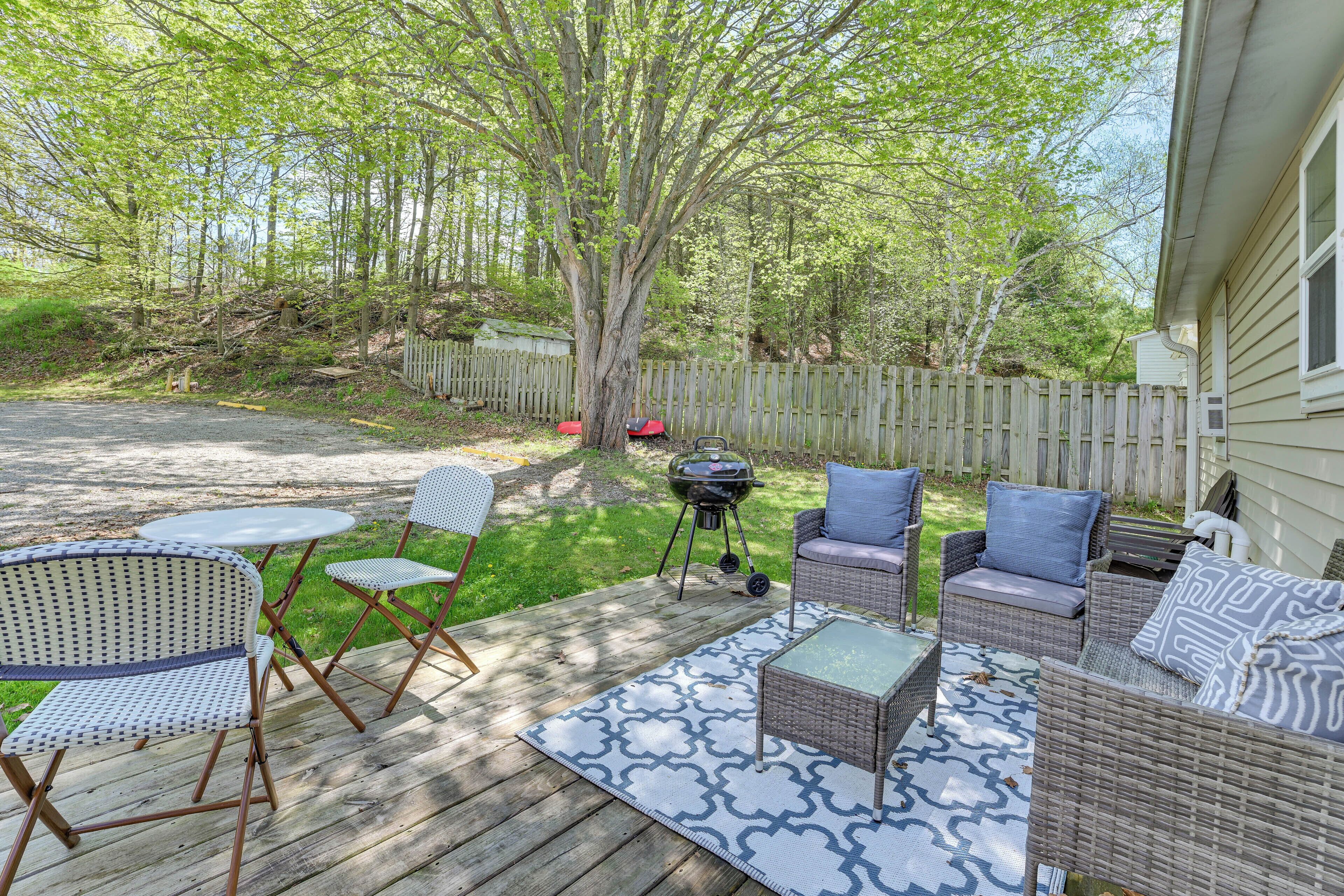 A wooden deck with outdoor furniture, including chairs and a sofa, and a grill.