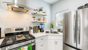 A modern kitchen with stainless steel appliances, white cabinetry, and a window providing natural light. - Small-town Charm & Patio Dining: Home in Madera! (Madera)