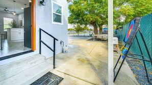 A residential entryway with a concrete patio, a door leading to a kitchen, and a view of a tree and parked cars. - Small-town Charm & Patio Dining: Home in Madera! (Madera)