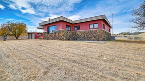 A two-story house with a stone foundation and red siding, situated on a grassy hill with a clear sky. - 1 Mi to Hot Springs State Park: Rustic Wyoming Gem (Thermopolis)