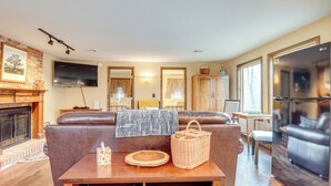 Una sala de estar con chimenea, televisor, sofá, mesa de centro y refrigerador.