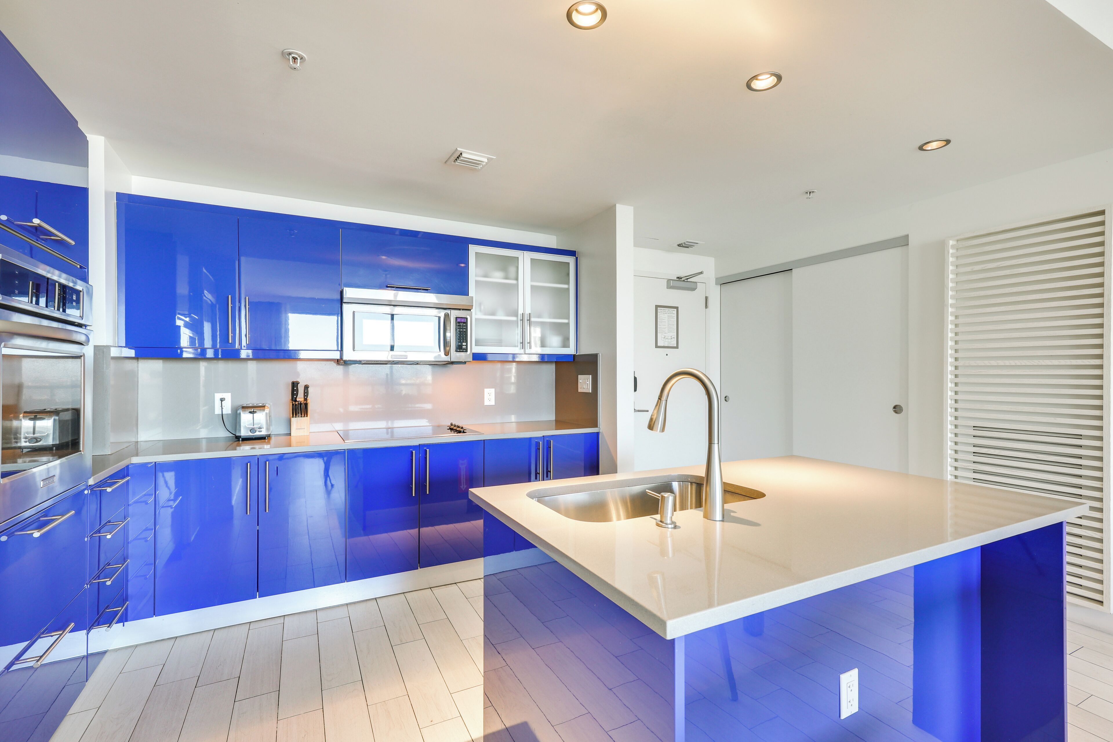 Una cucina moderna con mobili azzurri, elettrodomestici in acciaio inossidabile e un'isola centrale con lavello.