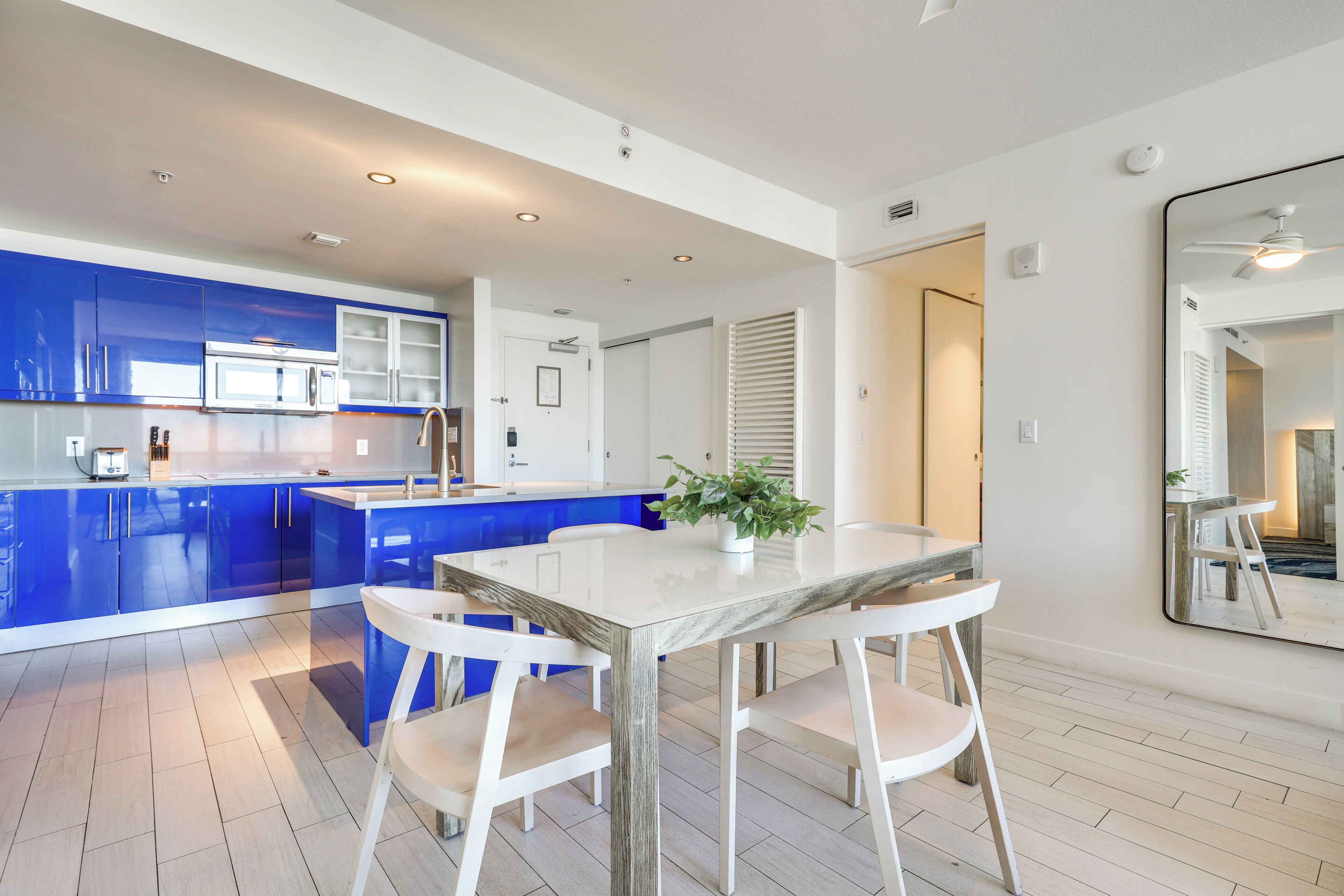 Una cocina moderna con armarios azules, una mesa de comedor blanca y una planta en maceta.