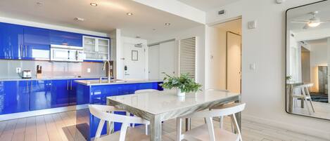 Una cocina moderna con armarios azules, una mesa de comedor blanca y una planta en maceta.