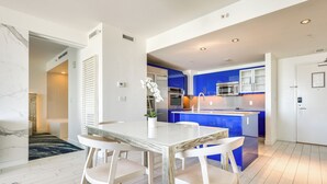 A modern kitchen with blue cabinets, a central island, and white appliances. - Sleek Fort Lauderdale Condo Near Beaches & Dining! (Fort Lauderdale)
