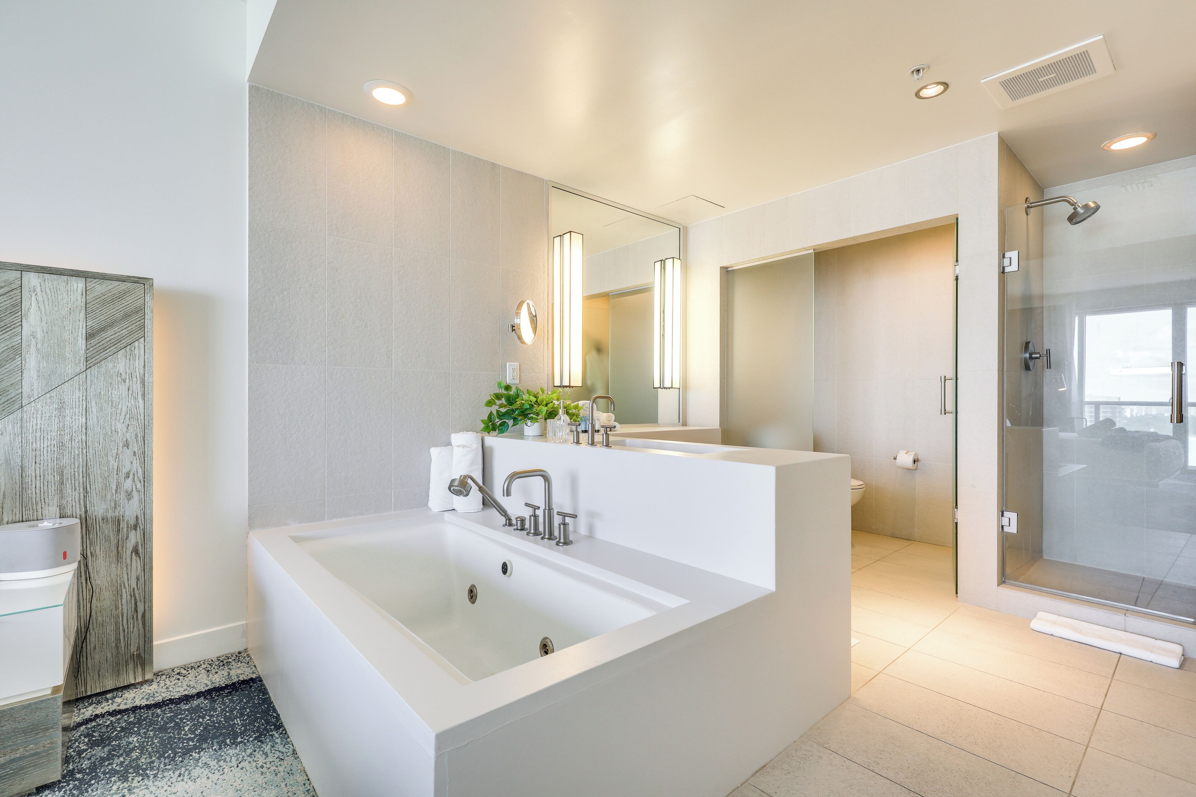 Un baño moderno con una bañera grande, cabina de ducha con paredes de vidrio y un espejo amplio.