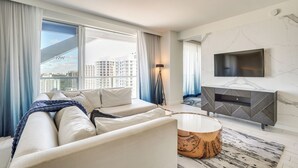 A modern living room with a sofa, a round coffee table, and a TV mounted on the wall. - Sleek Fort Lauderdale Condo Near Beaches & Dining! (Fort Lauderdale)
