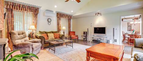 A spacious living room with a ceiling fan, a television, and a dining area with chairs and a table.